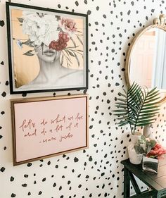 two framed pictures hang on the wall above a small table with a potted plant