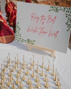 a table topped with lots of gold bells and a sign that says, reg it's ball wish them all