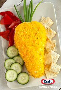 a white plate topped with cheese and crackers next to cucumbers