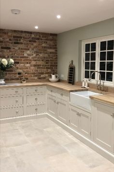 a large kitchen with white cabinets and wooden counter tops, along with a brick wall