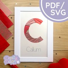 the letter c is made out of red ribbon and paper on top of a wooden table