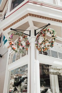 wreaths are hanging on the side of a building in front of a window display