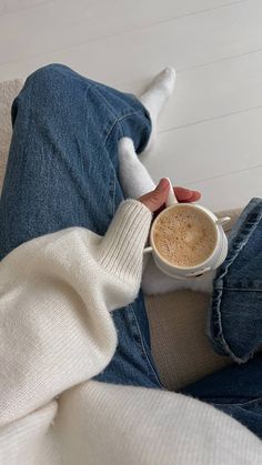 a person sitting on a couch holding a cup of coffee