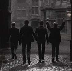 four men in suits are walking down the street