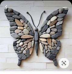 a butterfly made out of rocks sitting on top of a wall