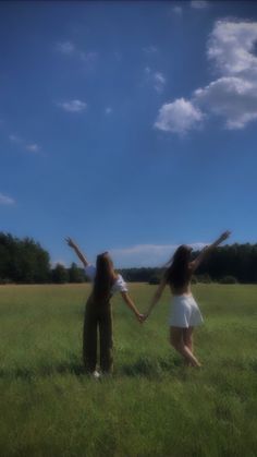 two people standing in a field with their arms spread out to each other and one person holding the other's hand