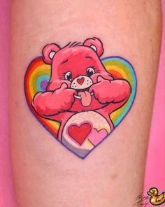 a pink teddy bear with a rainbow heart tattoo on the left side of her leg