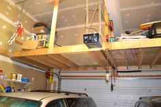 a car is parked in front of a garage with two overhead shelves on the ceiling