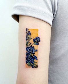 a person with a tattoo on their arm that has blue flowers in the shape of a letter