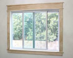 an empty room with a large window on the wall and trees in the back ground