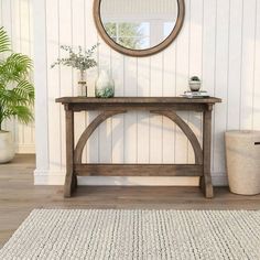 a wooden table sitting in front of a mirror on top of a white rug next to a potted plant