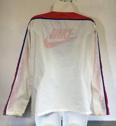 Here's a classic vintage Nike windbreaker! A large Nike logo is printed on back. The red, white, and blue color combo is perfect! There is a Nike tag inside the large front zipper pocket with the added bonus of being able to stuff the whole jacket into the pocket, zip it up, and peace out with your pouch! It shows some general wear---small marks, a hole at the pit seam, graphic wear, etc. But overall the fabric is in good condition and it has tons of fun left in it! Check out other sensational v Red Nylon Sporty Track Jacket, Red Nylon Sportswear Track Jacket, Red Nylon Track Jacket, Retro Nylon Track Jacket For Streetwear, Vintage Spring Sports Windbreaker, Retro White Track Jacket For Sports, Retro White Track Jacket For Outdoor, Retro Red Sports Windbreaker, Retro Nylon Track Jacket For Outdoor