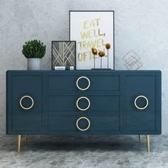 a blue dresser with gold handles and rings on the drawers is shown in front of a gray wall