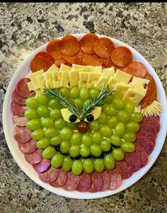 a plate filled with grapes, meats and cheese on top of a countertop