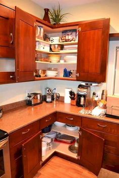 a kitchen with wooden cabinets and an open drawer in the corner that is filled with dishes