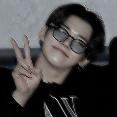 a person wearing glasses making the peace sign with their hand while sitting on a couch