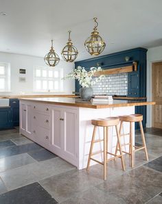 a kitchen with two stools in front of the island and blue cabinets on both sides