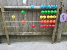 an outdoor game made out of plastic balls and wooden pegs on the side of a fence