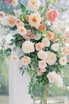 a bride holding a bouquet of pink and white flowers with greenery in the background