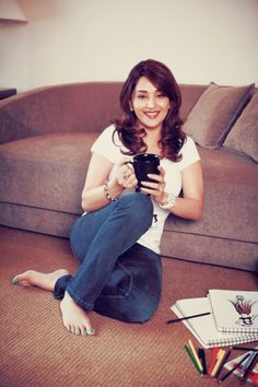 a woman sitting on the floor with her cell phone in her hand and looking at the camera