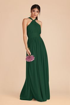 a woman in a long green dress holding a pink bouquet and looking at the camera