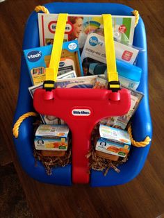 a child's toy car seat filled with toys and books on top of a wooden floor