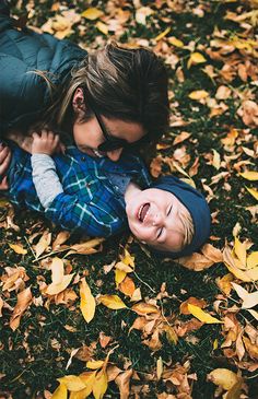 two young children laying on the ground with leaves all around them and one is holding his head