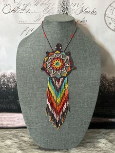 a beaded necklace is displayed on a mannequin's neckline, with an ornament in the center