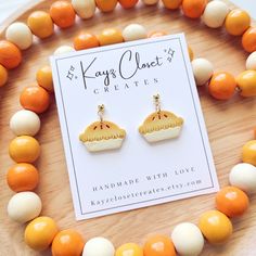 an orange and white beaded necklace with matching earrings on top of a wooden tray