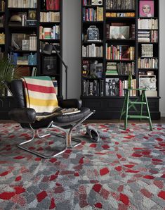 a living room filled with lots of bookshelves next to a chair and table