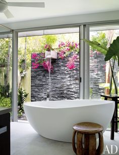 a large white bath tub sitting in a bathroom next to a window with pink flowers on it