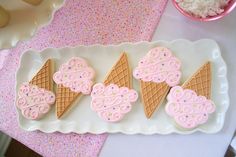 three ice cream cones decorated with pink icing and sprinkles on a white plate