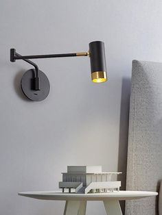 a table with a lamp on it next to a wall mounted light and a couch