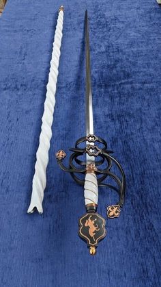 two swords are sitting on a blue carpeted floor, one is white and the other is black