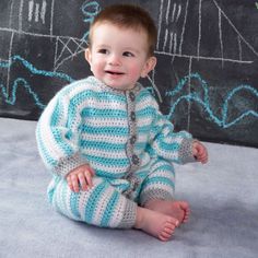 a baby sitting on the ground wearing a blue and white striped knitted outfit with buttons