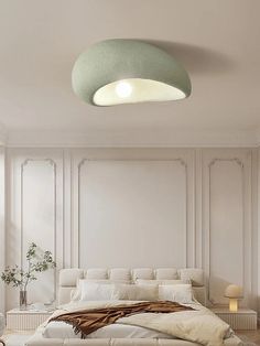 a large white bed sitting in a bedroom next to a wall mounted light above it