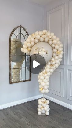 a balloon arch with white balloons hanging from it's sides in front of a mirror