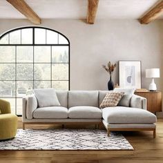 a living room with a sectional couch and two chairs in front of a large window