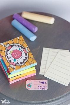 there is a small table with some pens and paper on it, along with two notebooks