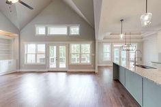 an empty kitchen and living room in a house with wood floors, white walls, and ceiling fan