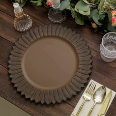 a brown plate sitting on top of a wooden table next to silverware and flowers