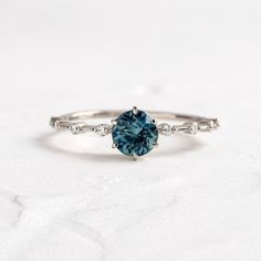 a white gold ring with a blue diamond