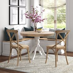 a dining room table with two chairs and a bench in front of the window next to it