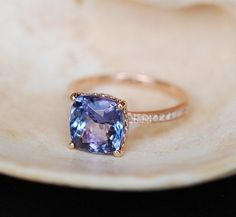 a tan gold ring with an amethorate and diamonds on the side, sitting on a plate