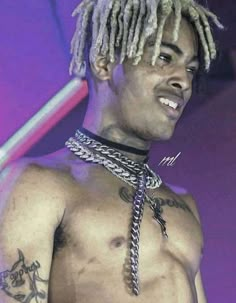 a shirtless man with dreadlocks on his chest