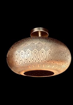 a light that is hanging from the ceiling in front of a black background with an intricate design on it