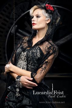 a woman in a black dress and red flower on her head is posing for the camera