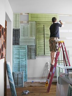 a man standing on a ladder painting the walls