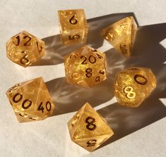 gold dices with numbers on them sitting on a white table top next to each other