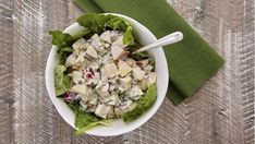 a white bowl filled with salad next to a green napkin